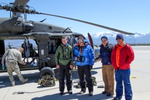 Four people smiling at a camera in front of a helicopter.