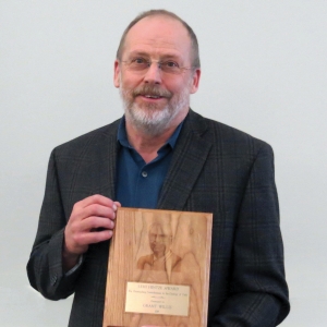 One person smiling at the camera with an award.