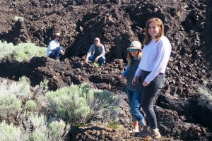 A group of four people smiling at the camera, at a lava flow in Black Rock Desert.