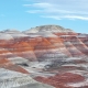 Striped orange, red, and gray hills under a pale blue sky.