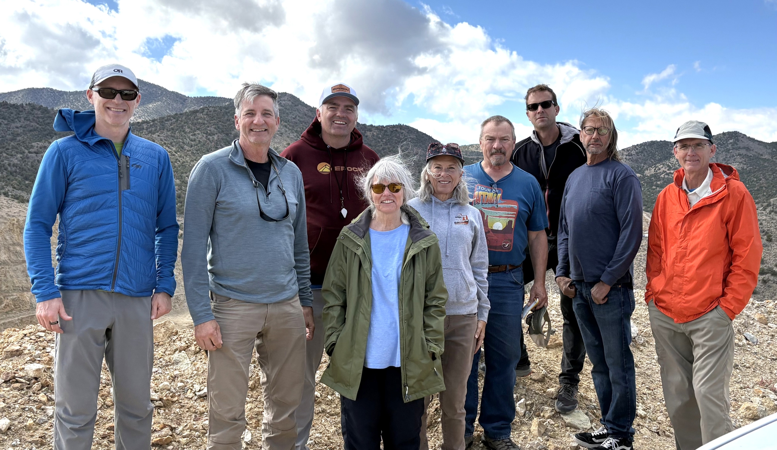 A group of people smiling outside with mountains in the background.