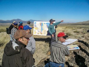 Multiple people in a field, with two people holding a geologic map.