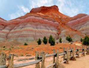 Red and orange striped cliffs above old wooden fencing.