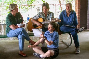 Group of people singing with a person holding a guitar.